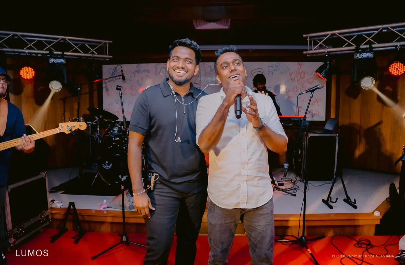 වේදිකාවේ දෙදෙනෙක් එකට මයික්‍රොෆෝනයක් අසල ගී ගයමින්